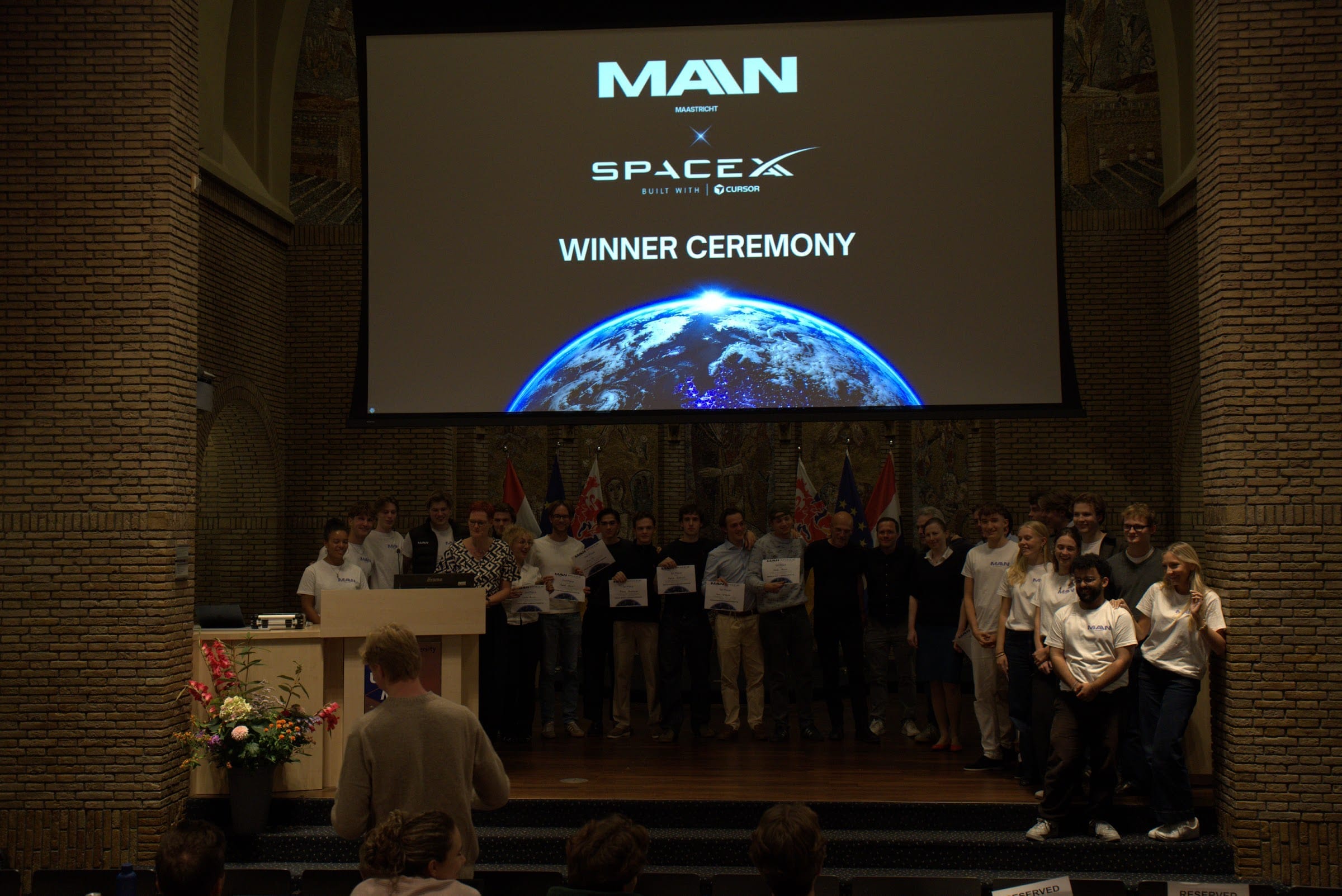 A group on stage under a MAIN × SpaceXAI slide at the close of the hackathon