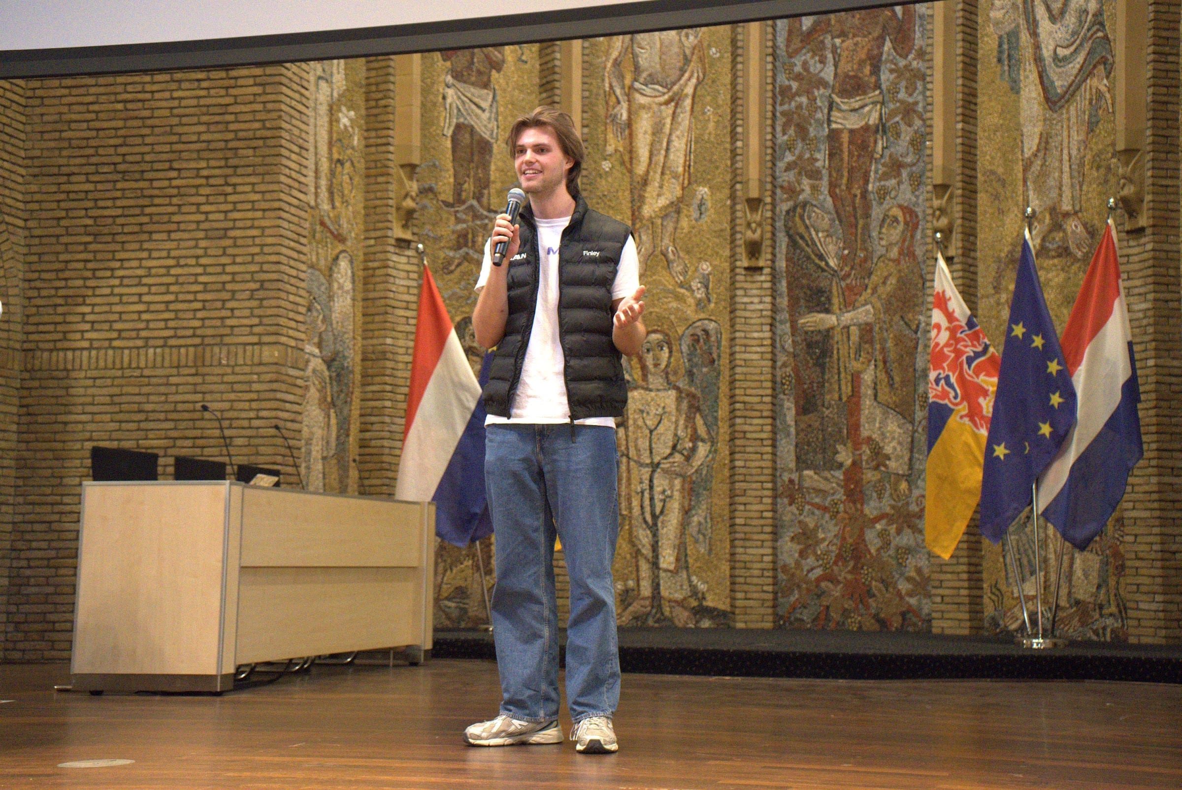 A MAIN organiser speaking on stage with a microphone at the SpaceXAI hackathon