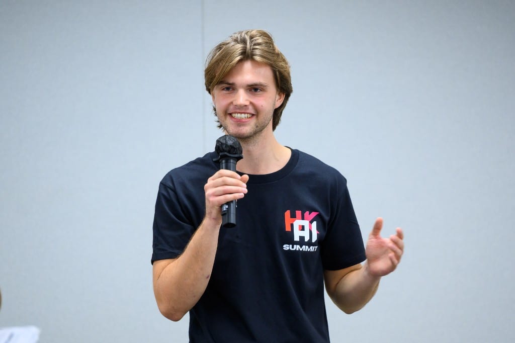 Finley Sieben speaking with a microphone at the Hong Kong AI Summit