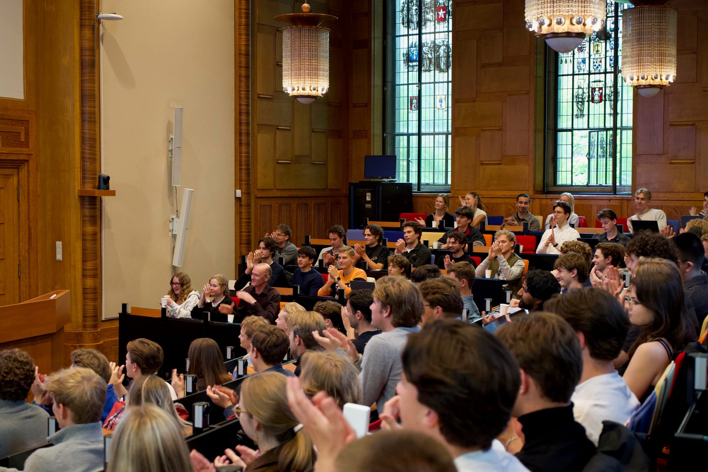 A full lecture hall of students applauding