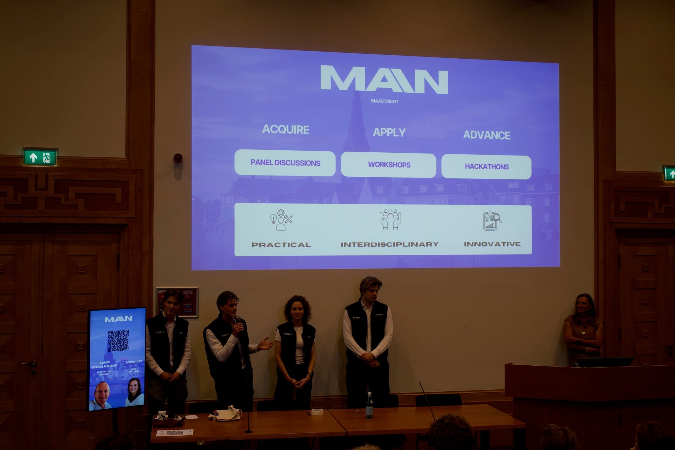 Four MAIN team members on stage in a lecture hall, introducing the network